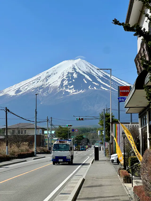 A bus travels along a quiet Japanese street with Mount Fuji in the distance