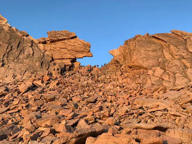 A jagged rock formation reaches into a cloudless blue sky