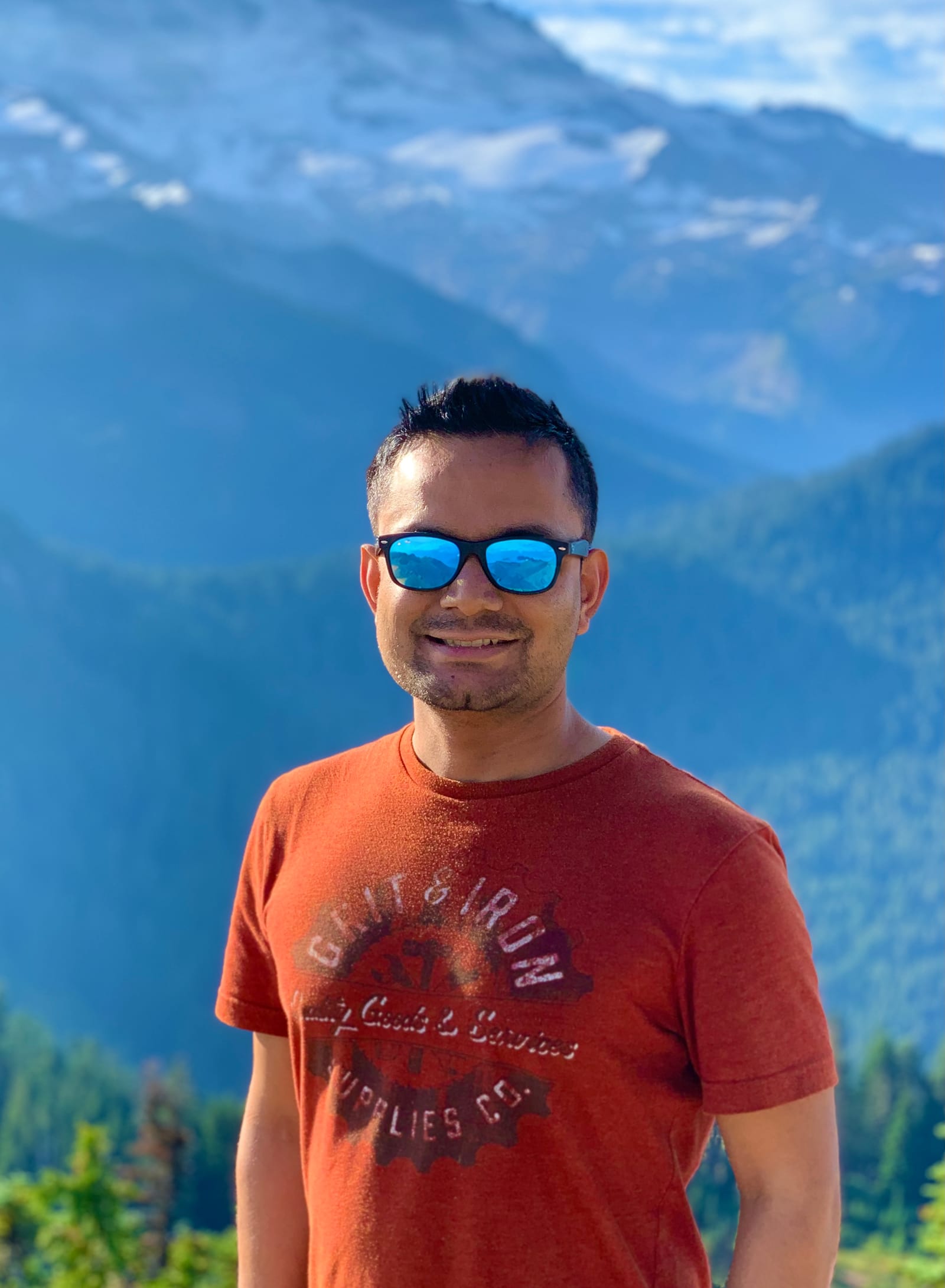 Portrait of Nitesh smiling in front of a mountain landscape