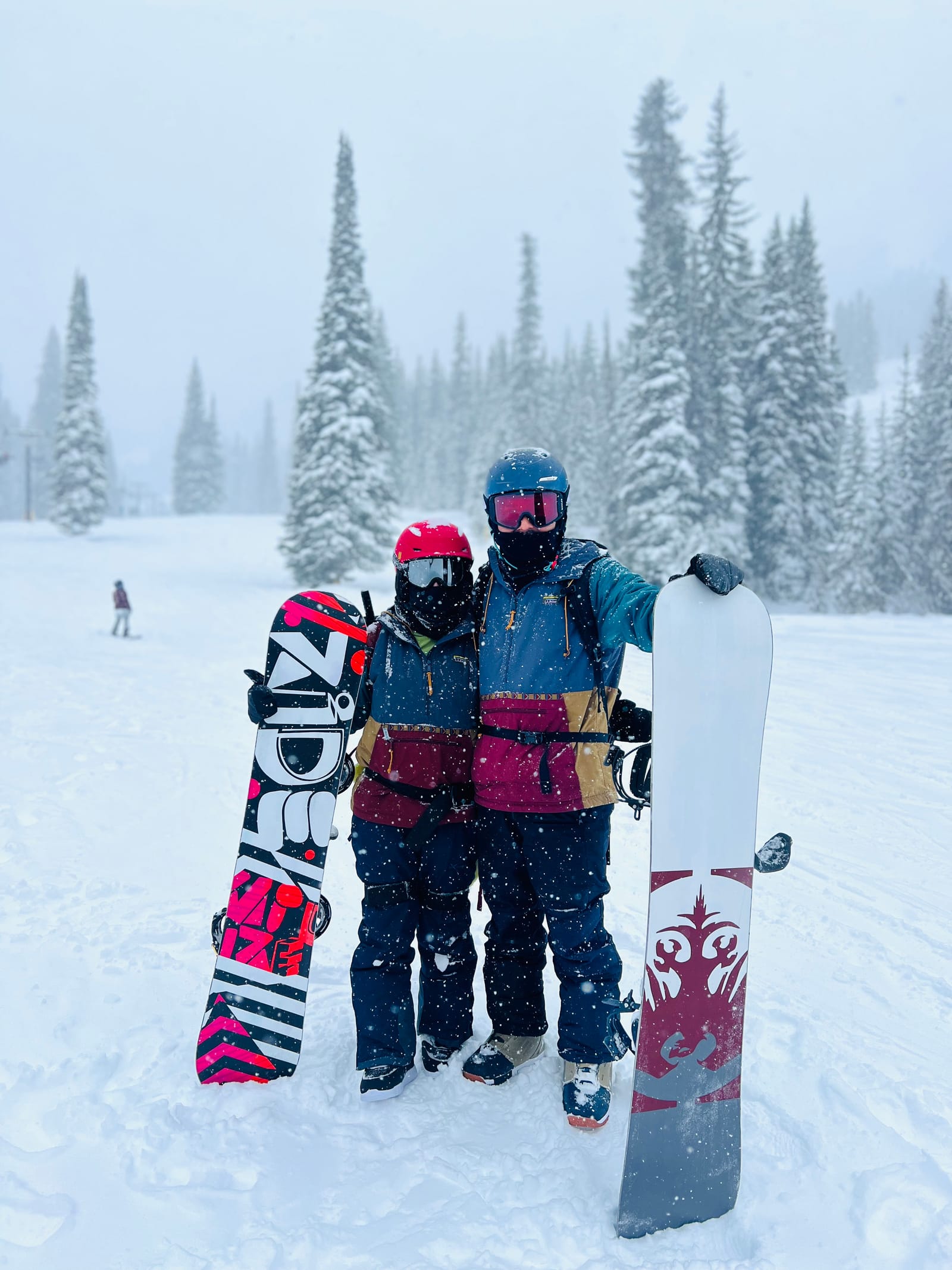 Two snowboarders standing together during falling snow